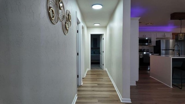 corridor with light hardwood / wood-style floors and sink