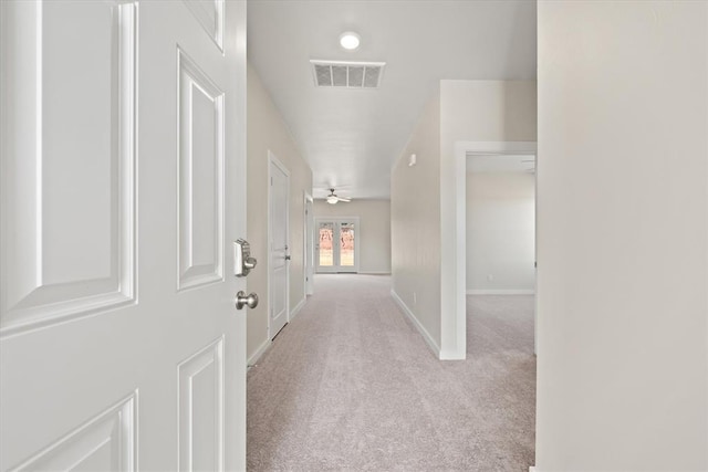 corridor with light carpet and french doors