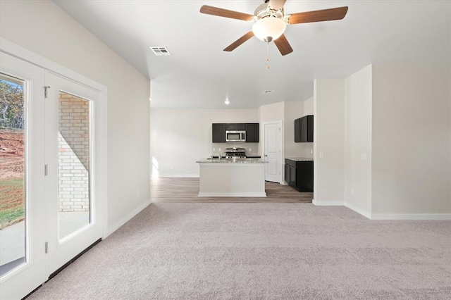 unfurnished living room featuring dark colored carpet and ceiling fan