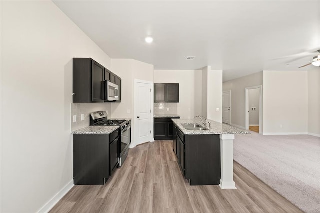 kitchen with backsplash, sink, ceiling fan, light stone countertops, and stainless steel appliances