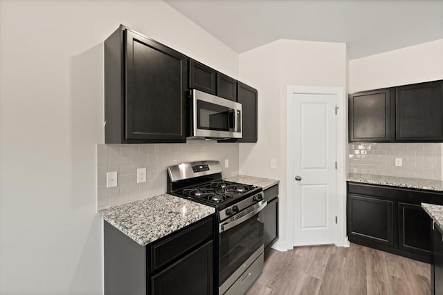 kitchen featuring backsplash, light stone countertops, light hardwood / wood-style flooring, and stainless steel appliances