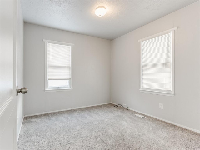 carpeted empty room with a textured ceiling