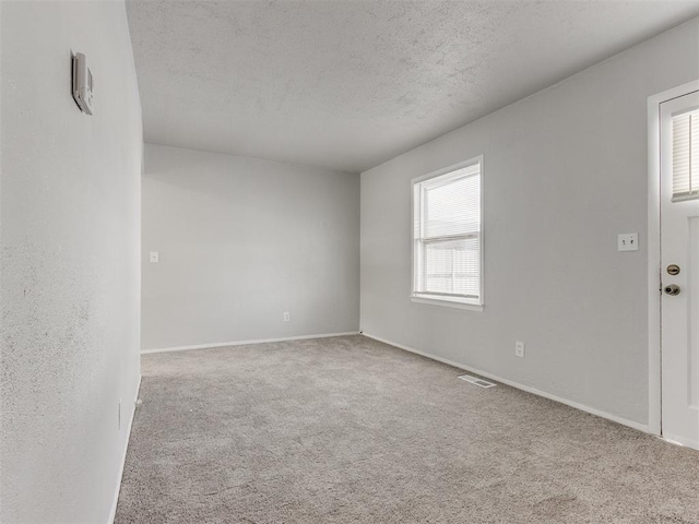 unfurnished room featuring light carpet and a textured ceiling