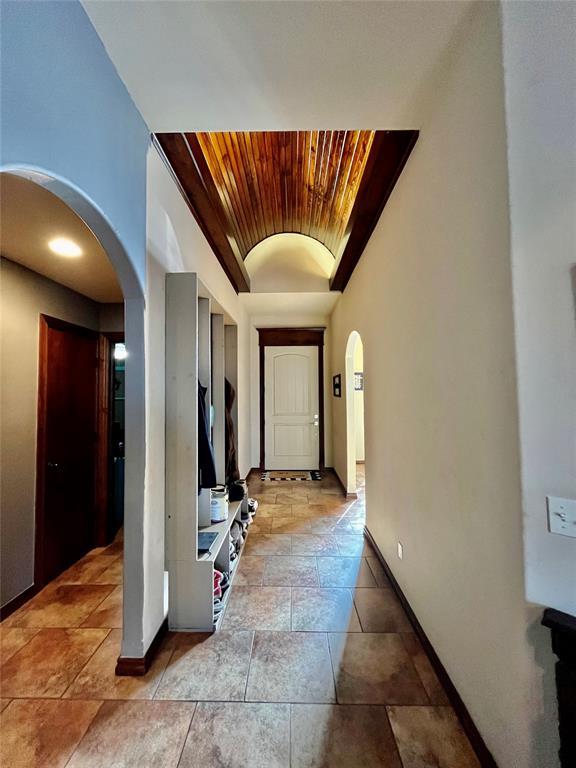 hallway featuring lofted ceiling and brick ceiling