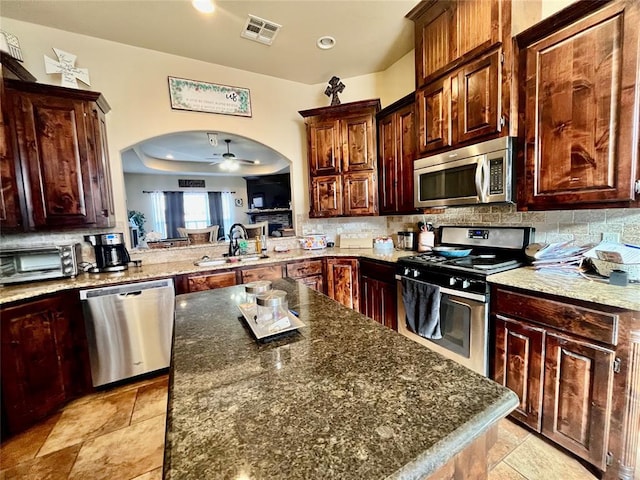 kitchen with a center island, stainless steel appliances, backsplash, ceiling fan, and sink