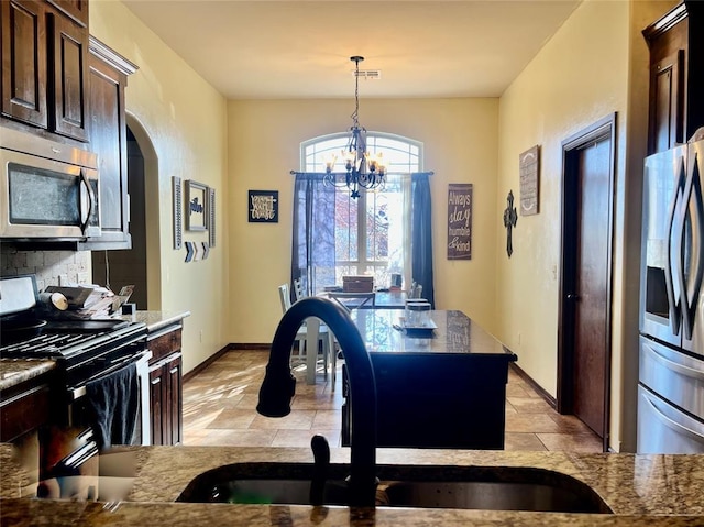 kitchen featuring stainless steel appliances, dark brown cabinetry, sink, an inviting chandelier, and decorative light fixtures