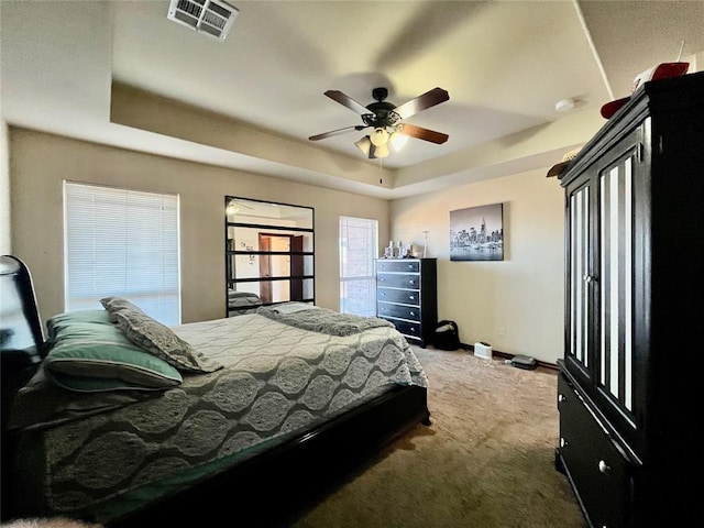 bedroom featuring a raised ceiling, ceiling fan, and dark colored carpet