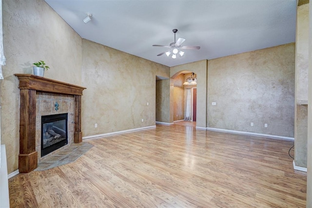 unfurnished living room featuring ceiling fan, light hardwood / wood-style floors, and a tiled fireplace