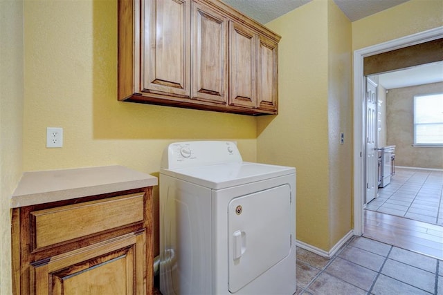 laundry area with light tile patterned floors, cabinets, and washer / dryer