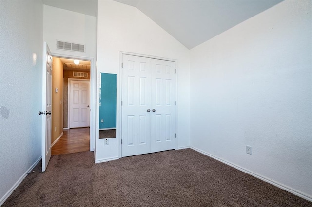 unfurnished bedroom with dark carpet, lofted ceiling, and a closet