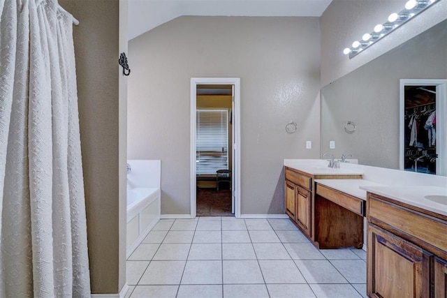 bathroom with tile patterned flooring, vanity, a bath, and vaulted ceiling