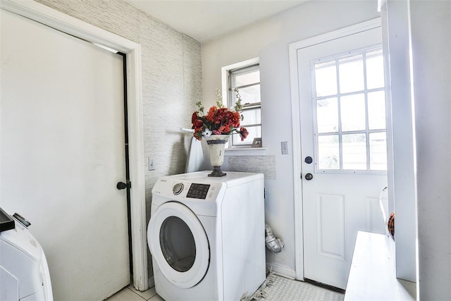 clothes washing area featuring light tile patterned floors and washer and clothes dryer