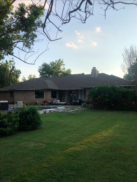 back house at dusk featuring a lawn and a patio