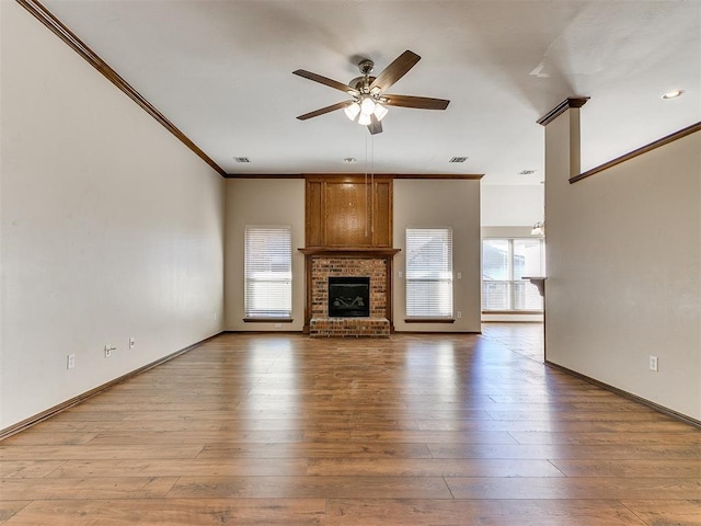 unfurnished living room with a brick fireplace, ceiling fan, ornamental molding, and light hardwood / wood-style flooring