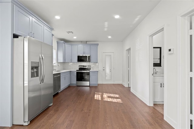 kitchen with sink, stainless steel appliances, tasteful backsplash, dark hardwood / wood-style flooring, and gray cabinets