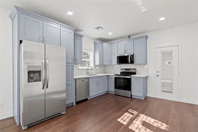 kitchen featuring tasteful backsplash, stainless steel appliances, dark wood-type flooring, sink, and gray cabinets