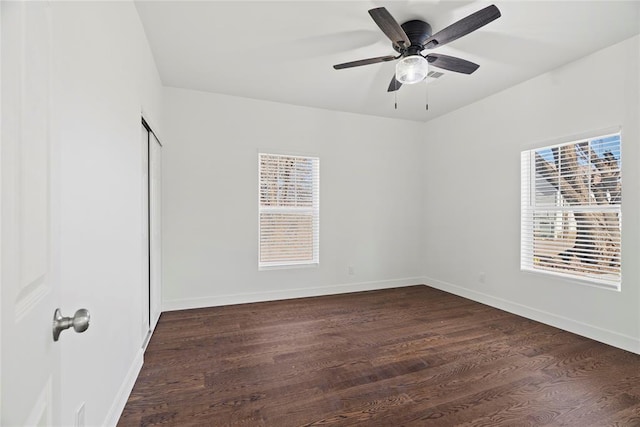 empty room featuring a wealth of natural light, dark wood-type flooring, and ceiling fan