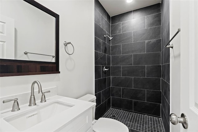 bathroom with tiled shower, vanity, and toilet