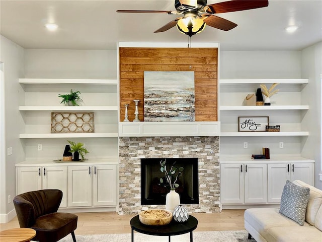 living room with a fireplace, built in features, light hardwood / wood-style floors, and ceiling fan