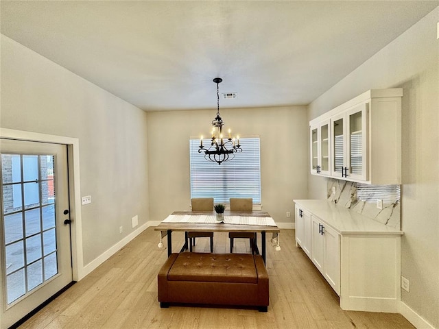 dining area with a chandelier, light hardwood / wood-style floors, and a healthy amount of sunlight