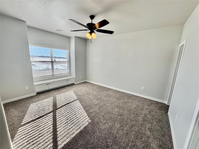 unfurnished room featuring ceiling fan, dark carpet, and a water view