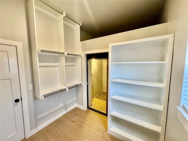 walk in closet with light hardwood / wood-style flooring