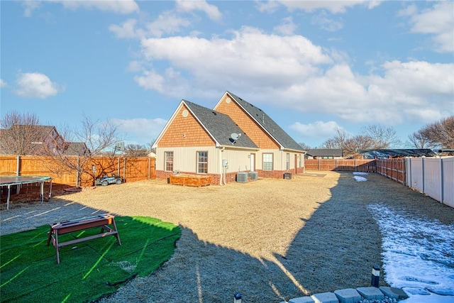 back of property with a trampoline and a fenced backyard