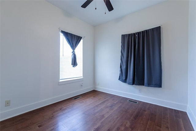 empty room with dark wood-style floors, baseboards, and visible vents