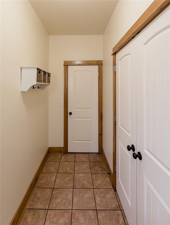 corridor featuring light tile patterned floors and baseboards