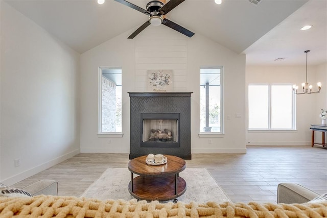 unfurnished living room with ceiling fan with notable chandelier, light hardwood / wood-style flooring, lofted ceiling, and a tiled fireplace