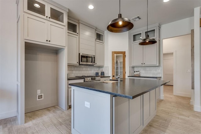 kitchen featuring sink, hanging light fixtures, an island with sink, white cabinets, and appliances with stainless steel finishes