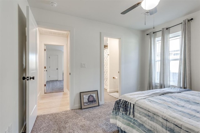 bedroom featuring connected bathroom, light carpet, and ceiling fan