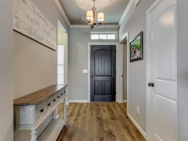 entryway with a chandelier, ornamental molding, and hardwood / wood-style flooring