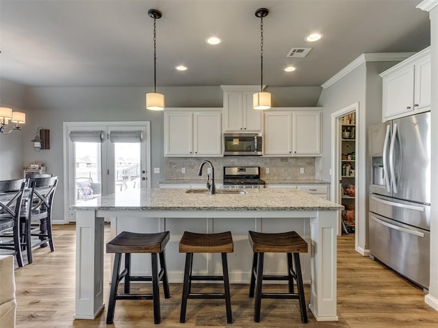 kitchen with appliances with stainless steel finishes, white cabinetry, hanging light fixtures, and sink