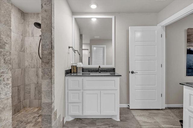 bathroom with a tile shower and vanity