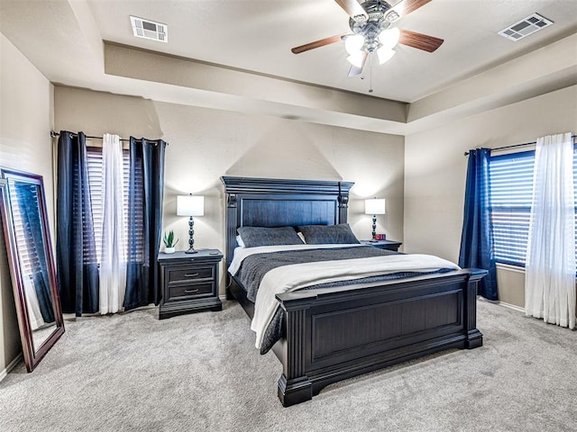 carpeted bedroom featuring ceiling fan and a raised ceiling