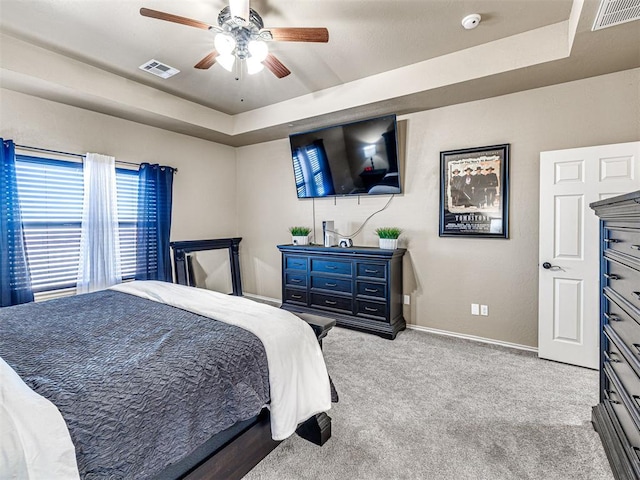 bedroom featuring ceiling fan, a raised ceiling, and light carpet