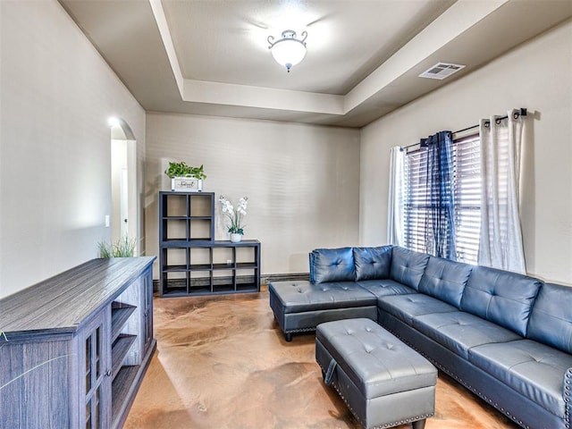 living room with arched walkways, visible vents, concrete flooring, and a tray ceiling