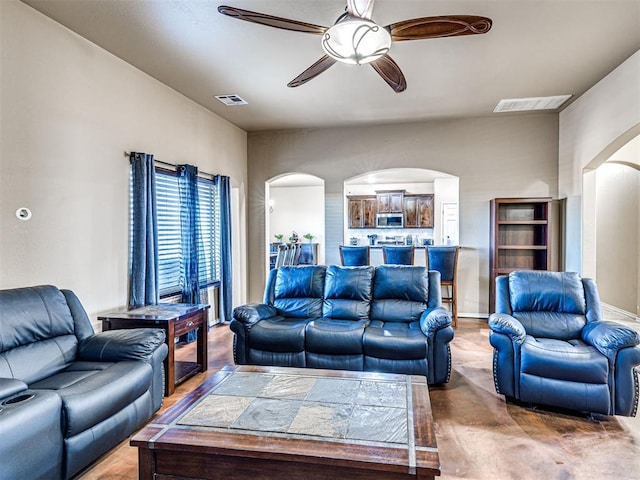 living room featuring visible vents, arched walkways, and a ceiling fan