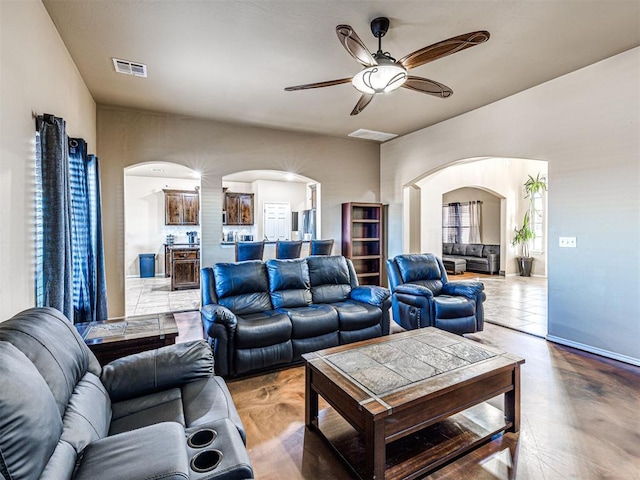 living area with visible vents, arched walkways, ceiling fan, and finished concrete floors