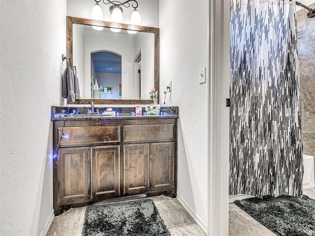 bathroom with vanity, a textured wall, and a shower