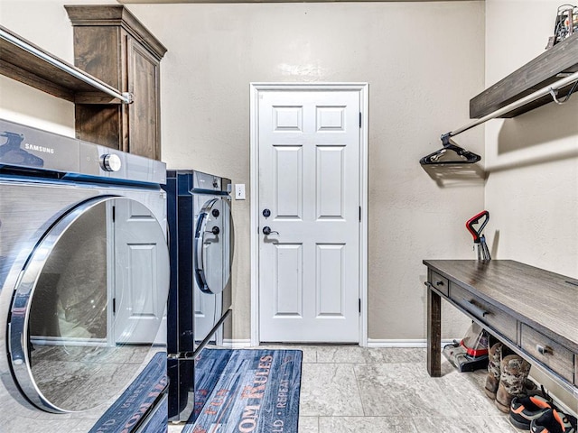 washroom featuring washer and dryer, baseboards, and cabinet space