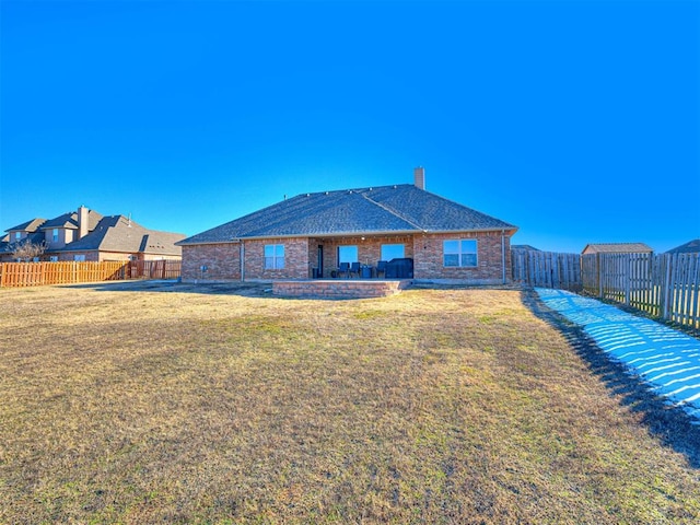 back of property featuring a patio, a fenced backyard, a lawn, and a chimney