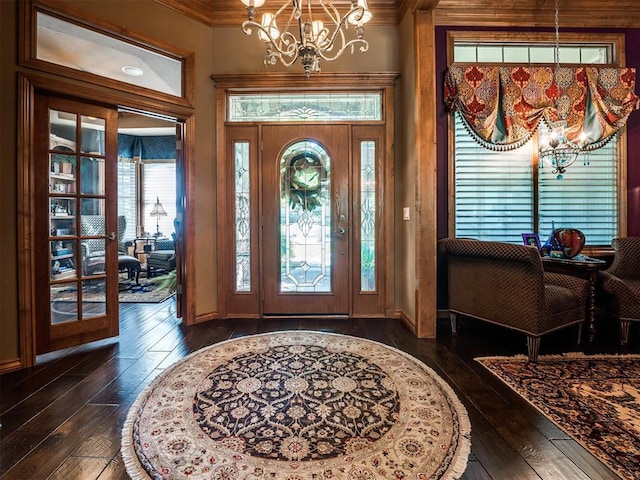 entryway with a chandelier, ornamental molding, dark wood-type flooring, and french doors