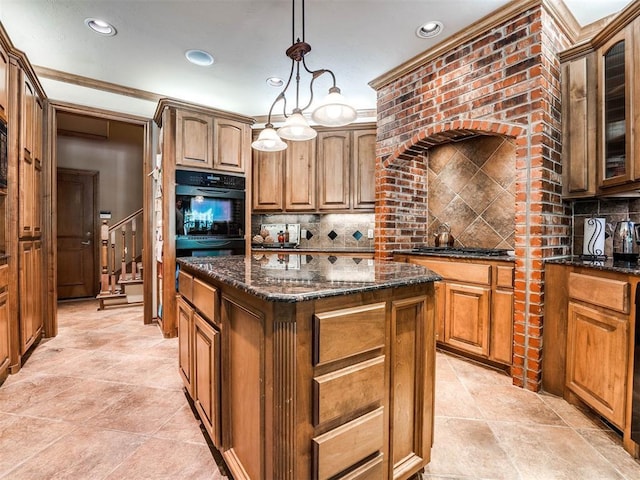 kitchen featuring a center island, decorative backsplash, dark stone countertops, ornamental molding, and decorative light fixtures