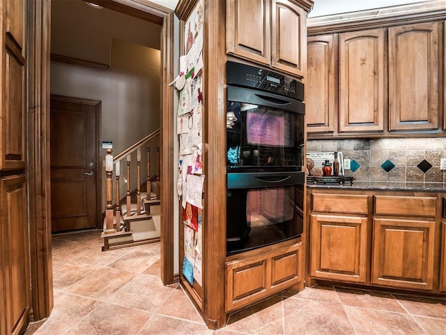 kitchen with black double oven, dark stone counters, and tasteful backsplash