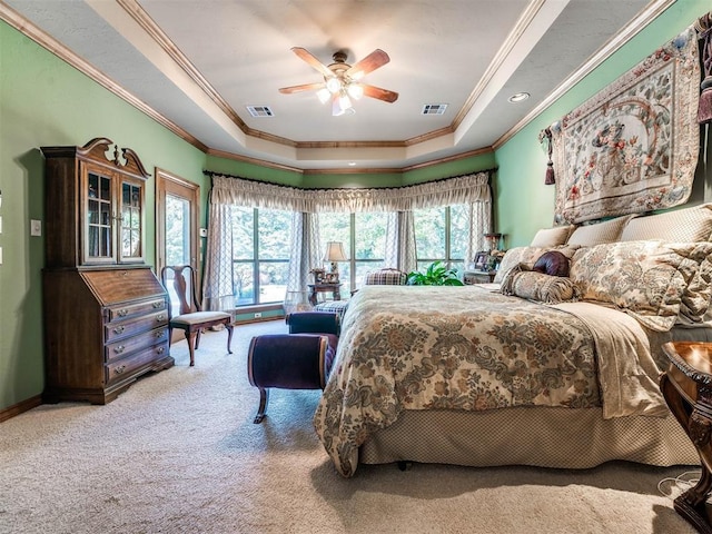 carpeted bedroom with a raised ceiling, ceiling fan, and ornamental molding