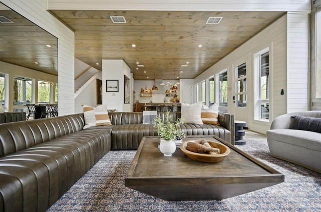 living room with a healthy amount of sunlight, wooden walls, and wooden ceiling