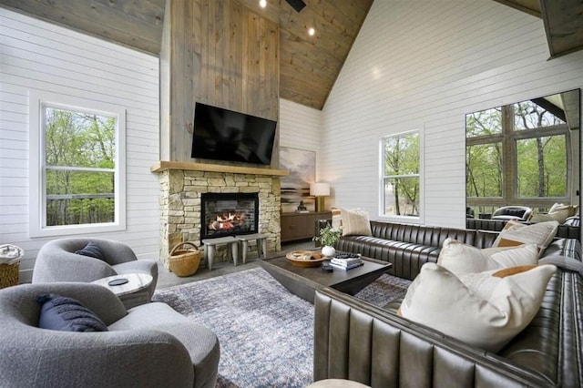 living room featuring high vaulted ceiling, wooden walls, wood ceiling, and a stone fireplace