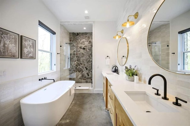 bathroom with tile walls, backsplash, vanity, and shower with separate bathtub